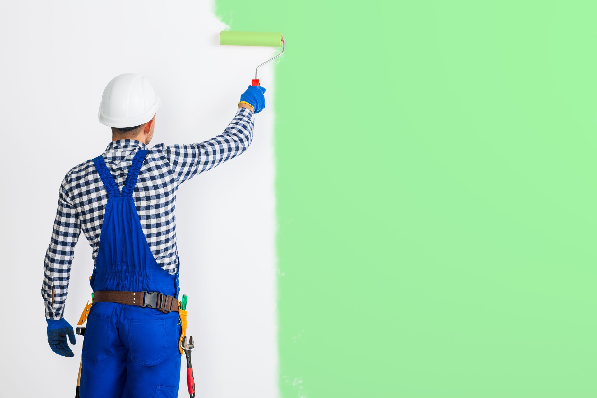Rear view of painter man painting the wall in green