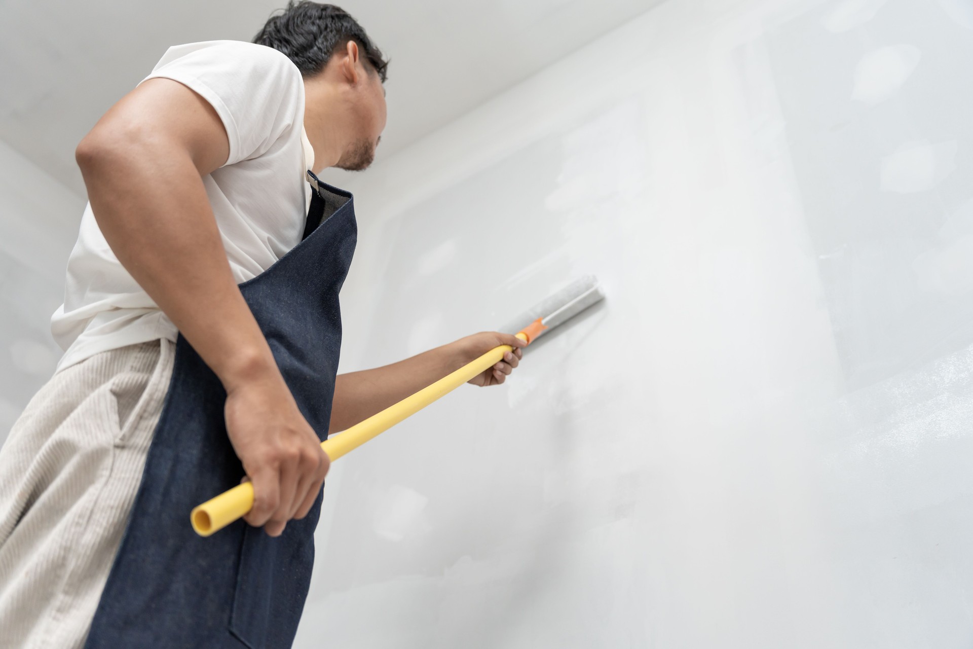 painter man, brush in hand for products to restore and paint the wall, indoor the building site of a house, wall during painting, renovation, painting, contractor, Architect, construction worker